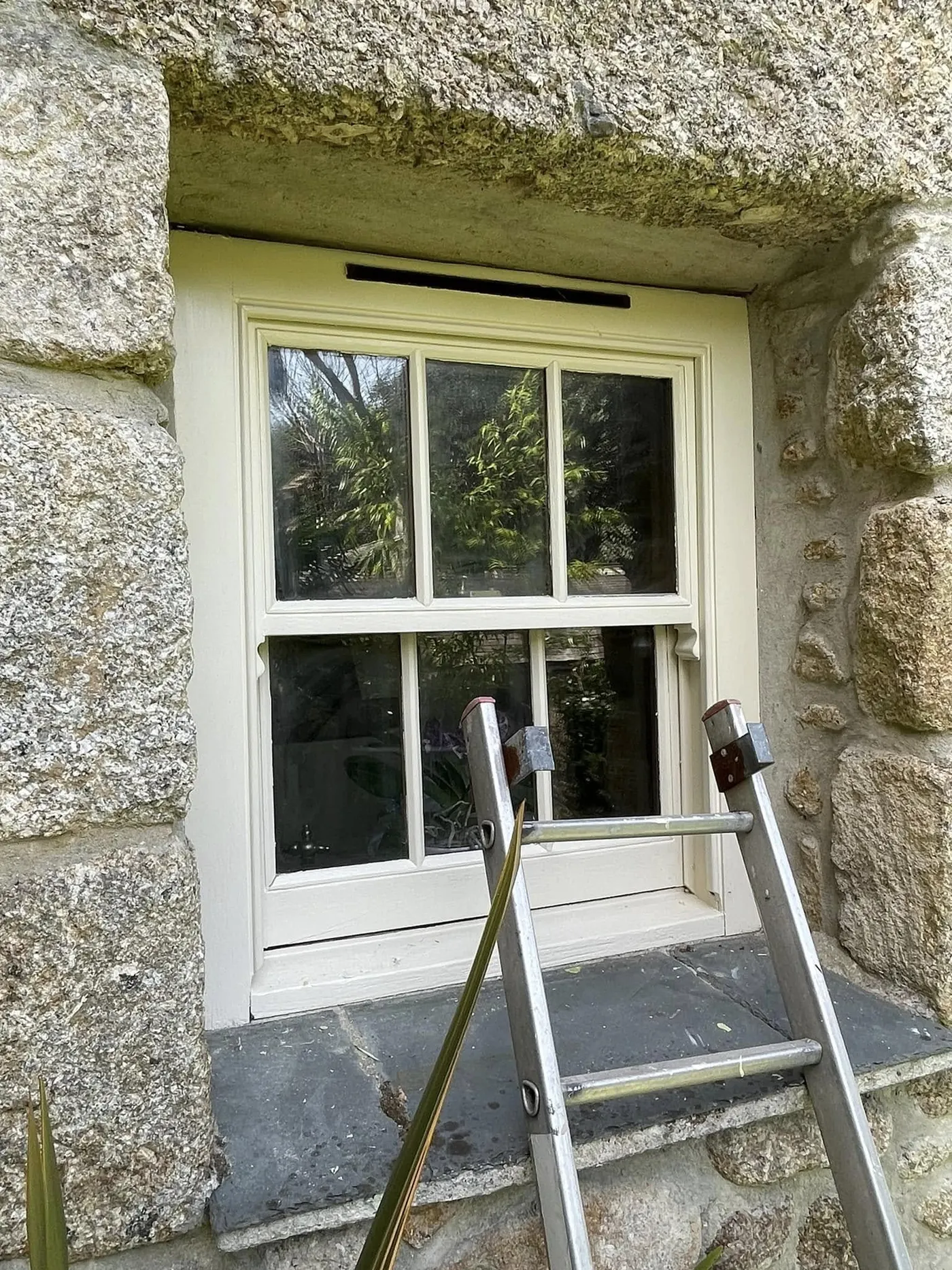 Restored white sash window in a granite wall